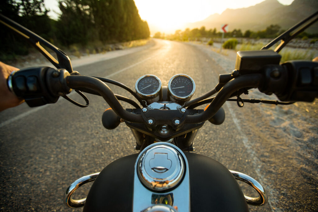 Traveling on a motorcycle on the road at sunset, point of view of the driver