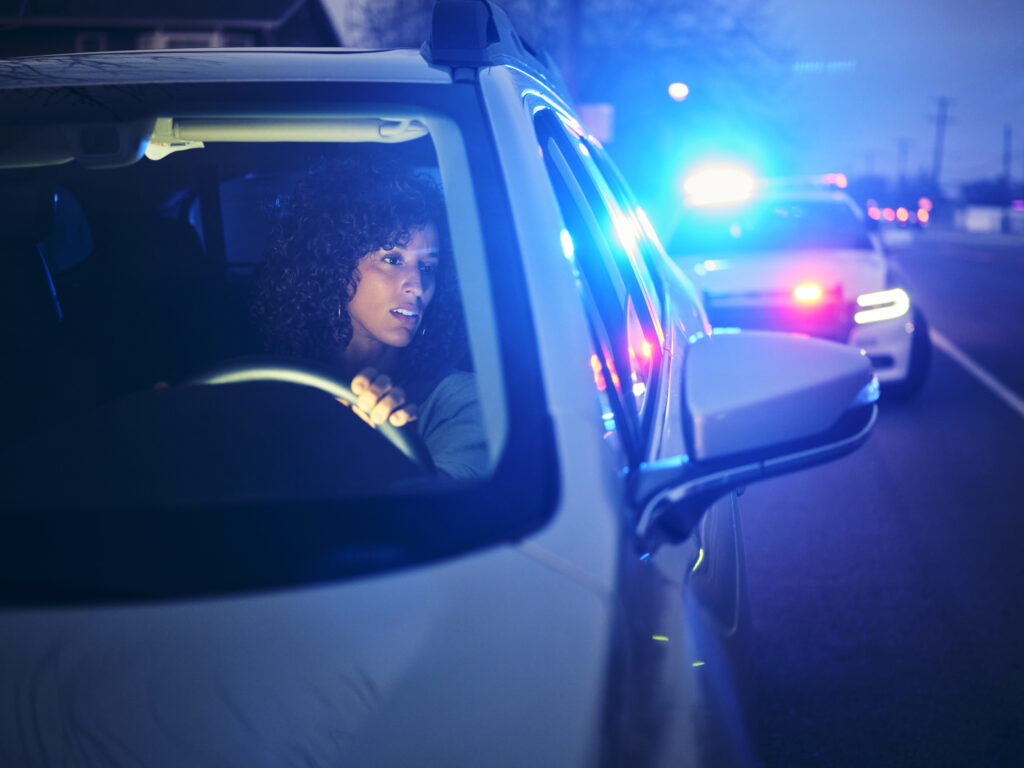 A young woman, being stopped by police at night for not having a license