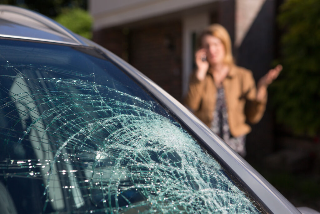 Woman Phoning her insurance company For Help After Car Windshield Has Broken in a car accident