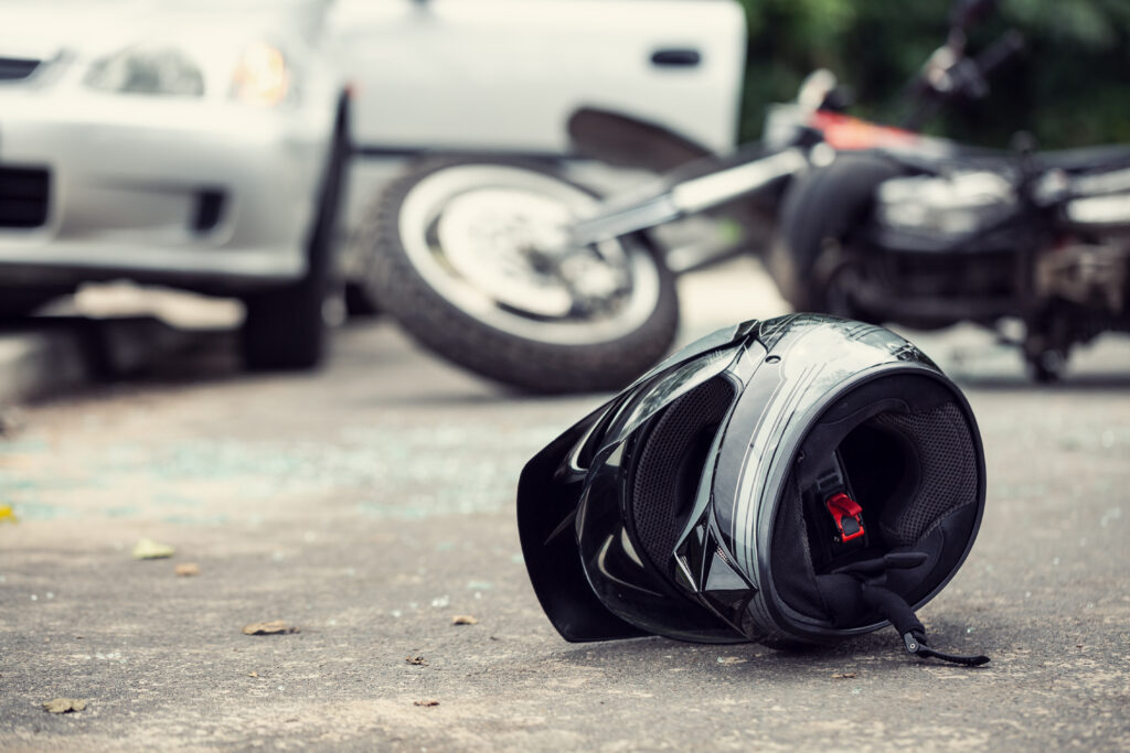 Close-up of a helmet of a driver with a blurred motorcycle and car in the background, motorcycle accident scene