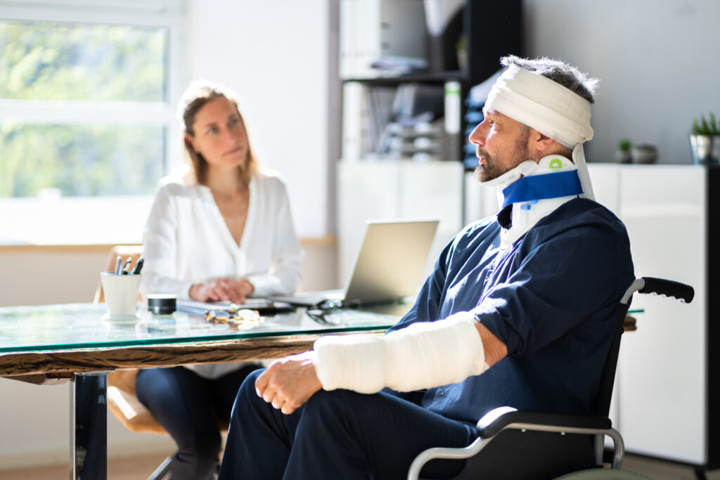 injured man talking to a personal injury lawyer about compensation. he has a cast on his arm and head after a personal injury accident