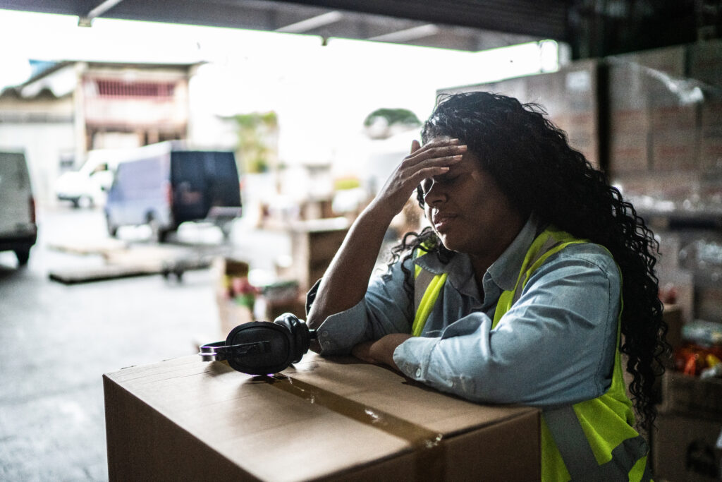Tired or worried female warehouse worker dealing with workers compensation claims