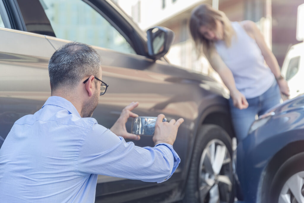 driver photographing car damage after a car accident 