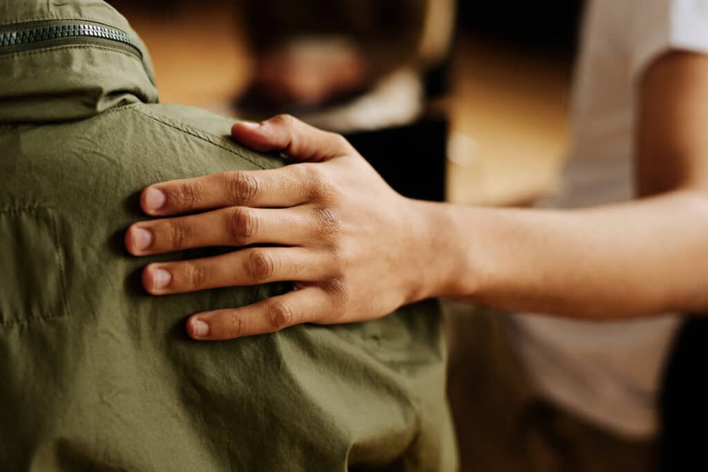 Hand of young supportive man consoling his friend after a wrongful death in his family, meeting with charlotte wrongful death lawyer
