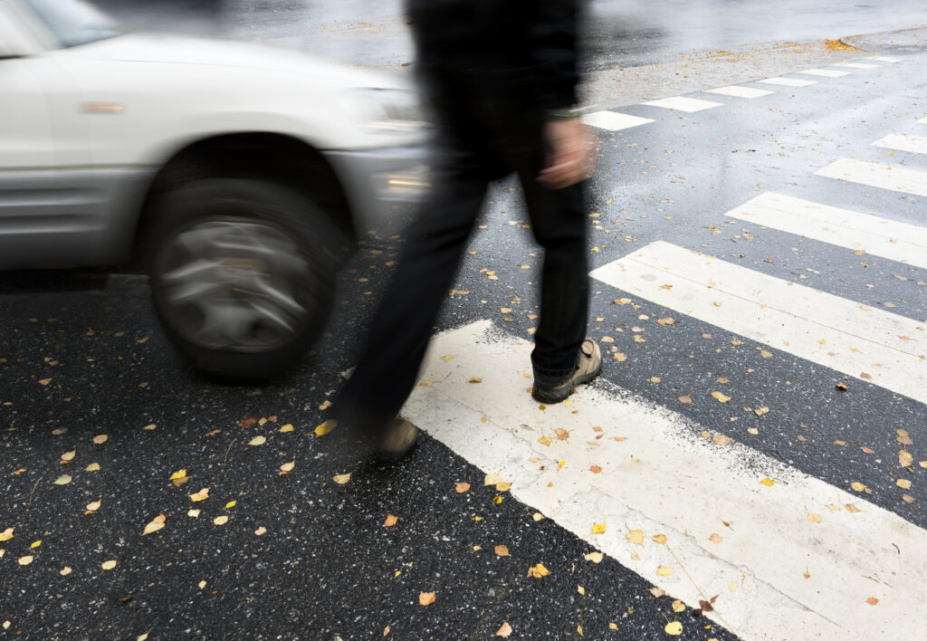 Man on pedestrian crossing in autumn, in danger of being hit by car, pedestrian accident scene