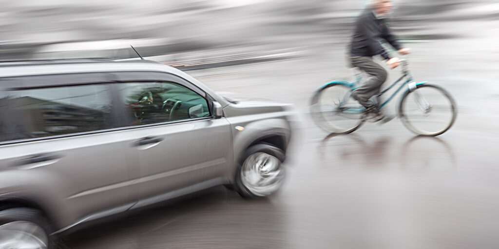 Dangerous city traffic situation with a cyclist and cars in motion blur, moments before a bicycle accident