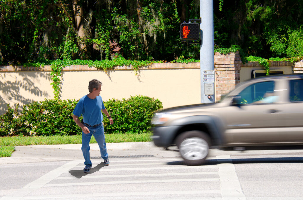 A man is jaywalking across an intersection when the signal is clearly showing the do not cross symbol.
