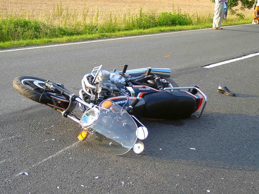 A motorcycle on the ground in the middle of the road after a motorcycle accident.