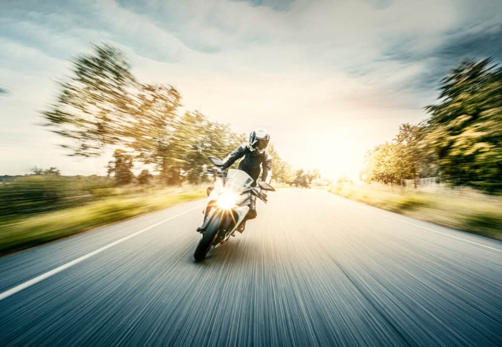 A motorcycle travels down a road at a high rate of speed.