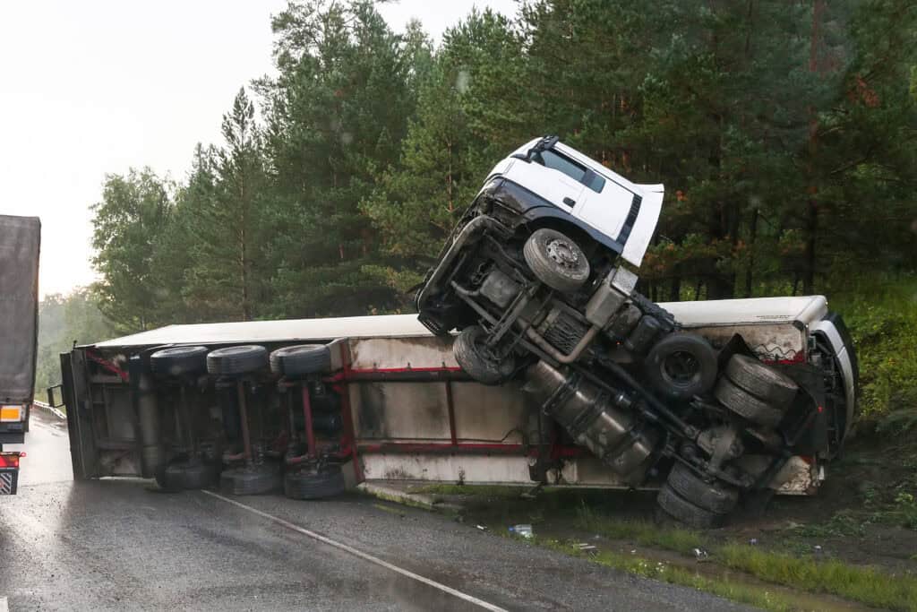 An overturned big-rig truck on the side of the highway after a jackknife truck accident.