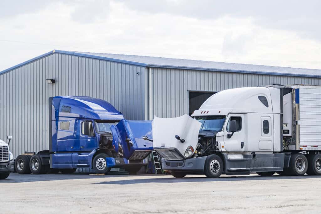 Large semi-trucks awaiting inspection outside of a large service station.