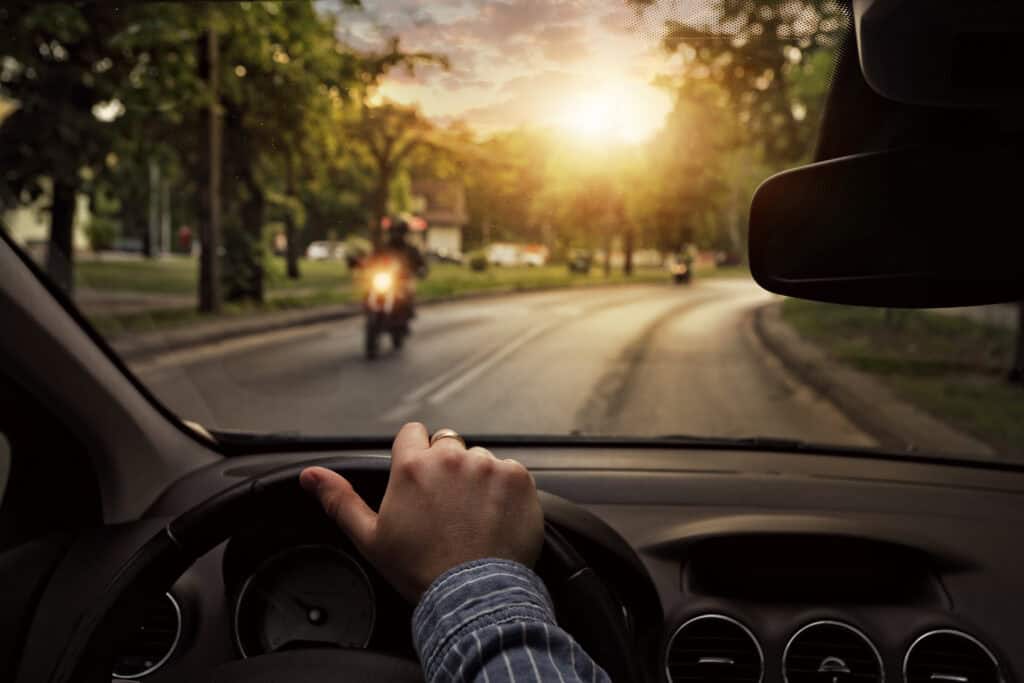 The view from inside a car driving down the road with motorcycles traveling in the opposite direction.